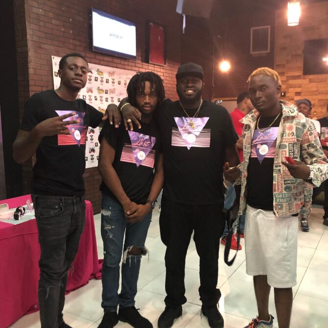 Black t-shirt featuring a purple triangle with the words “Let’s Get Lost in Miami” in retro 80s-style font, pink horizontal stripes, and pastel highlights representing a vintage South Beach aesthetic.