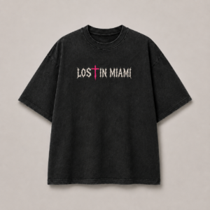 Front view of Lost in Miami God Is Real washed-black oversized tee with bone-white Gothic logo and neon-pink cross T